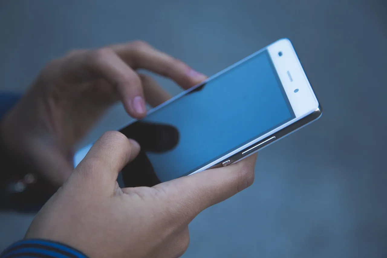 A person inspecting a smartphone screen to identify fake or refurbished phones in Pakistan